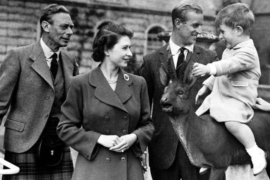 King George VI (left) stands besides Queen Elizabeth II and Prince Philip as Prince Charles sits on a horse