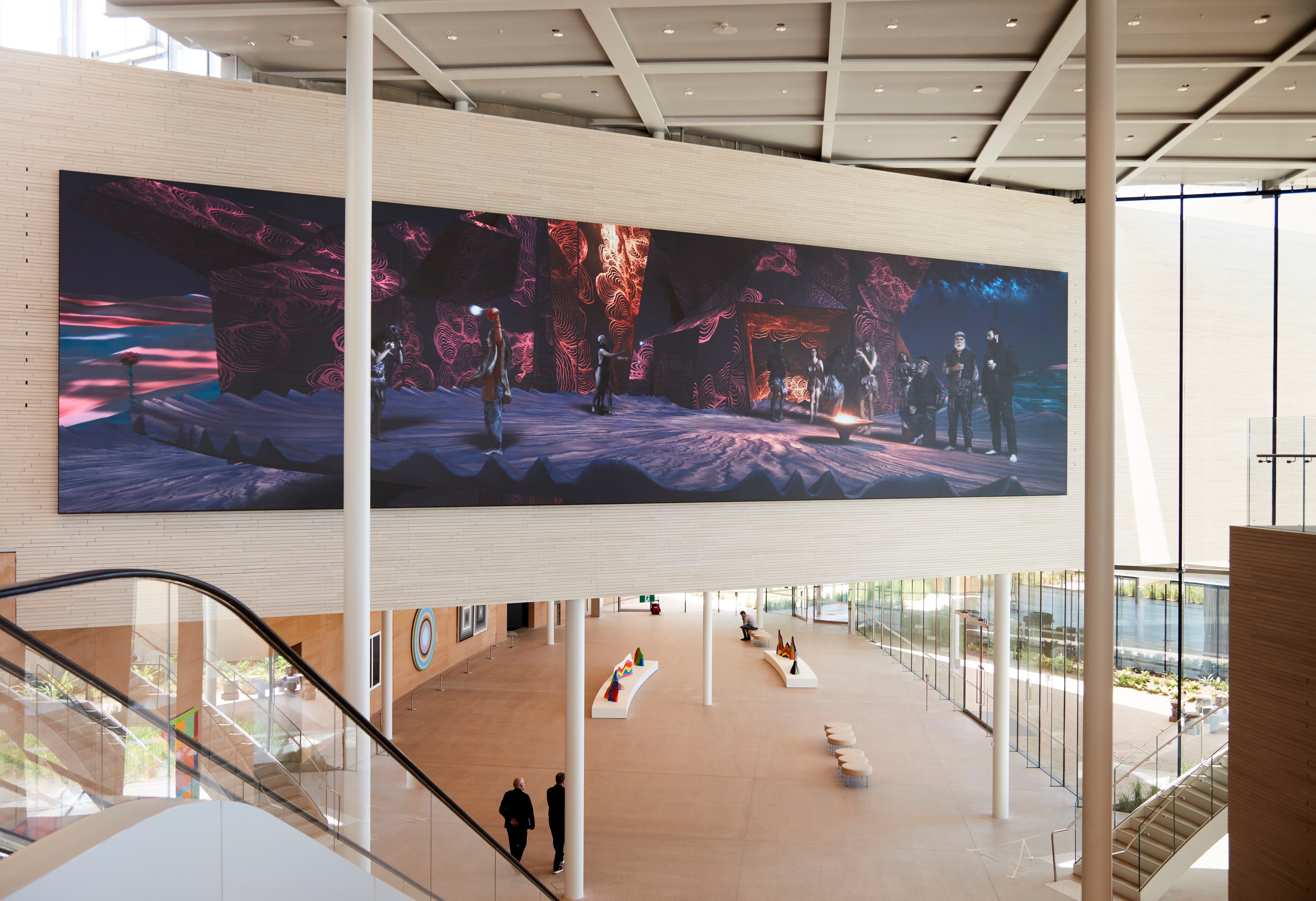A large rectangular artwork spans several metres of a gallery wall, featuring a nighttime scene in vivid pinks and purples.