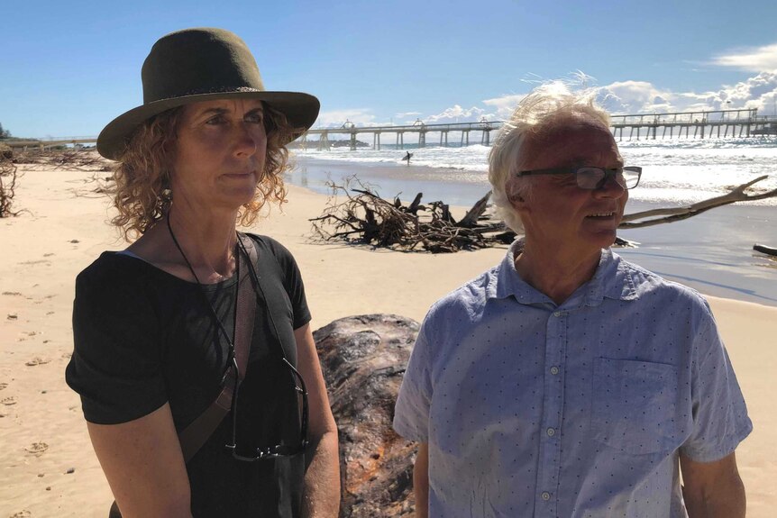Fingal residents Velia Hendry and Robert  Budd stand on the eroded beach at Fingal with the sand pumping jetty in the background