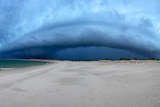 Dark clouds loom on the horizon over a beach