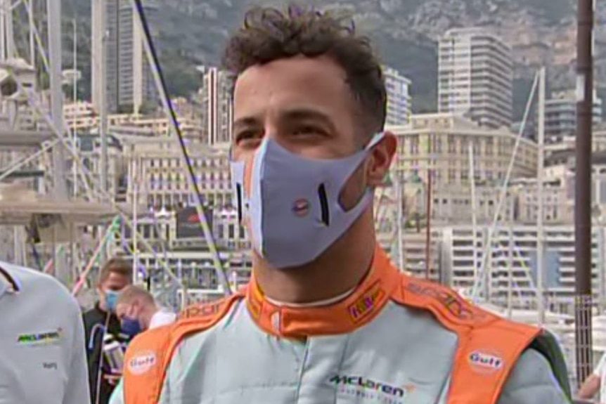 Racing driver wearing a face masks answers a journalist's question.