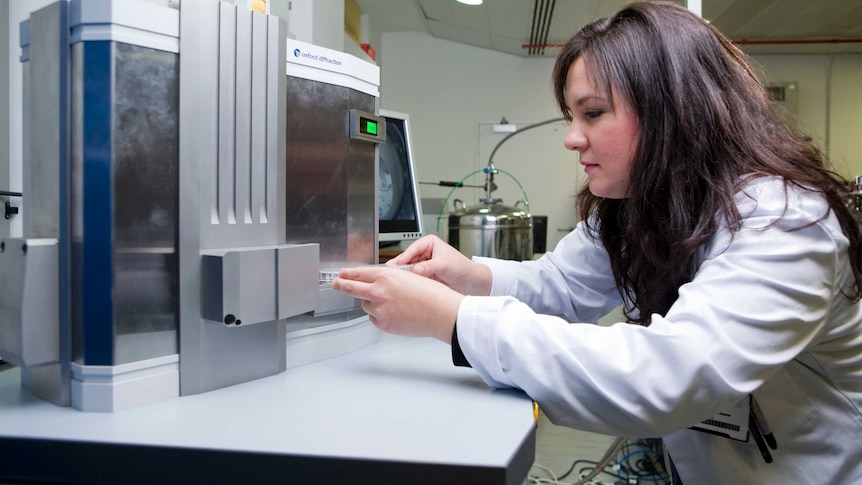 Scientist Nyssa Drinkwater at work in her laboratory wearing a white coat.