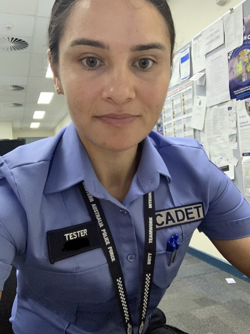 A woman wearing a police cadet uniform sits at a desk