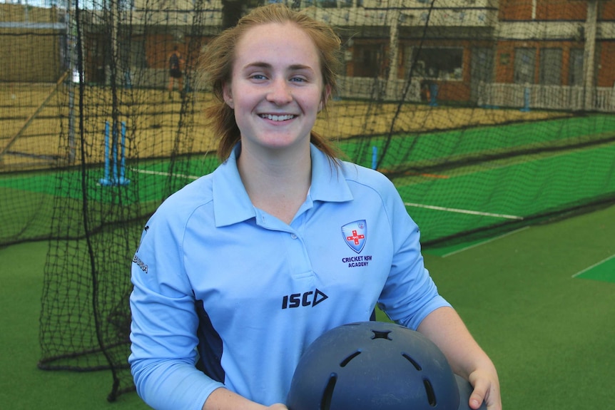 17-year-old NSW cricketer Yardley Polsen standing in the cricket nets holding her helmet.