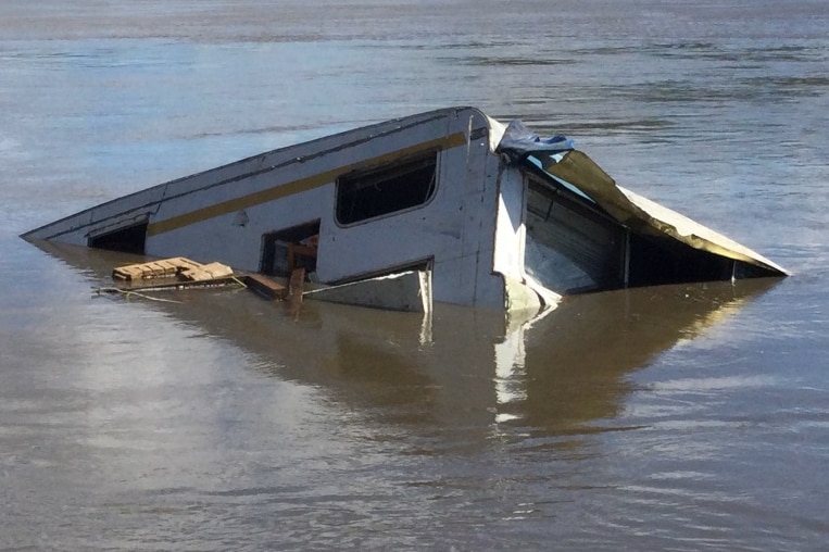 A partially submerged caravan in a river.
