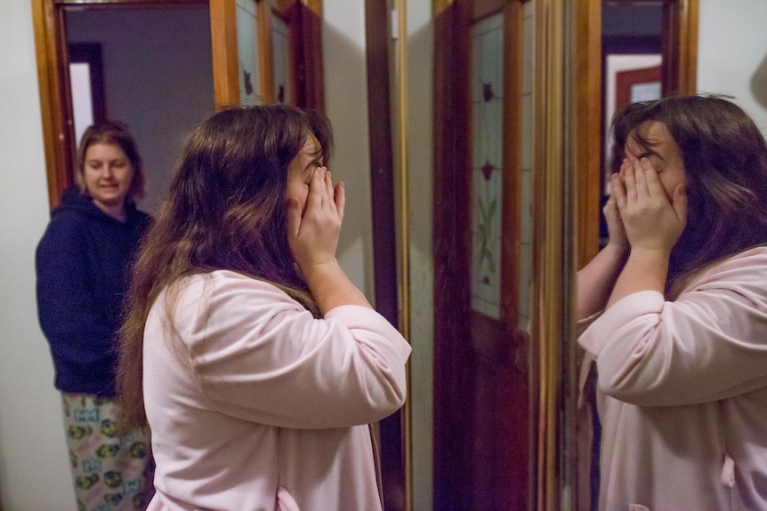 Student Shannon Colee rubs her eyes as she looks in the mirror.