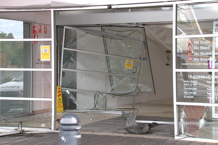 Glass sliding doors showing extensive damage at the entrance to a shopping centre