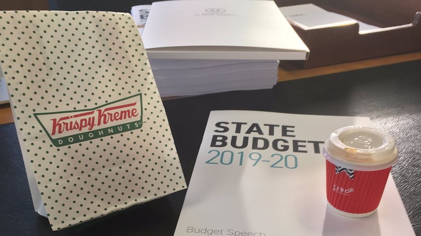 A bag of doughnuts and a coffee and budget documents