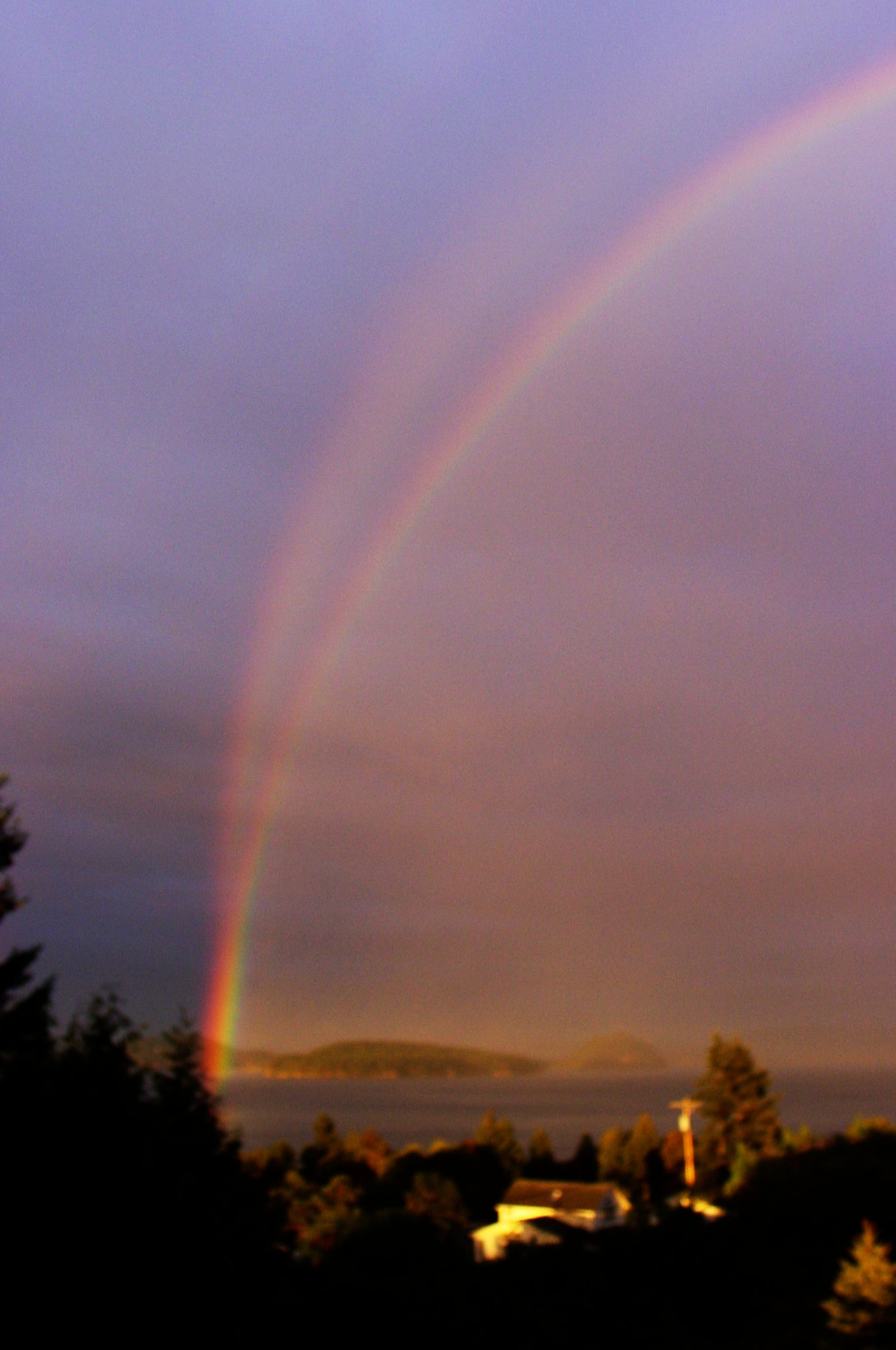 A typical rainbow with one next to it pointing upwards towards the sky.