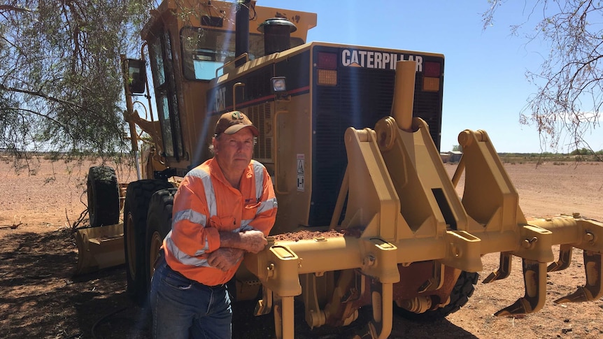 Barry Turner leaning on his new yellow tractor that he uses to manipulate the soil for the EMU project