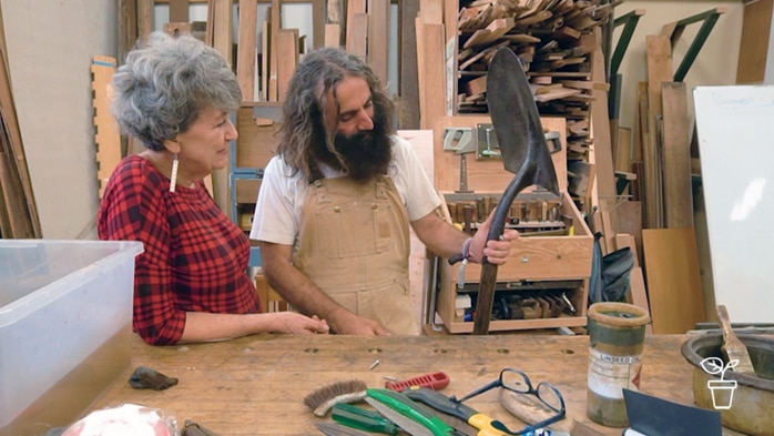 Man in overalls standing with a woman in a workshop