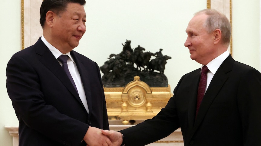 Xi, left, and Putin shake hands in a pose for cameras