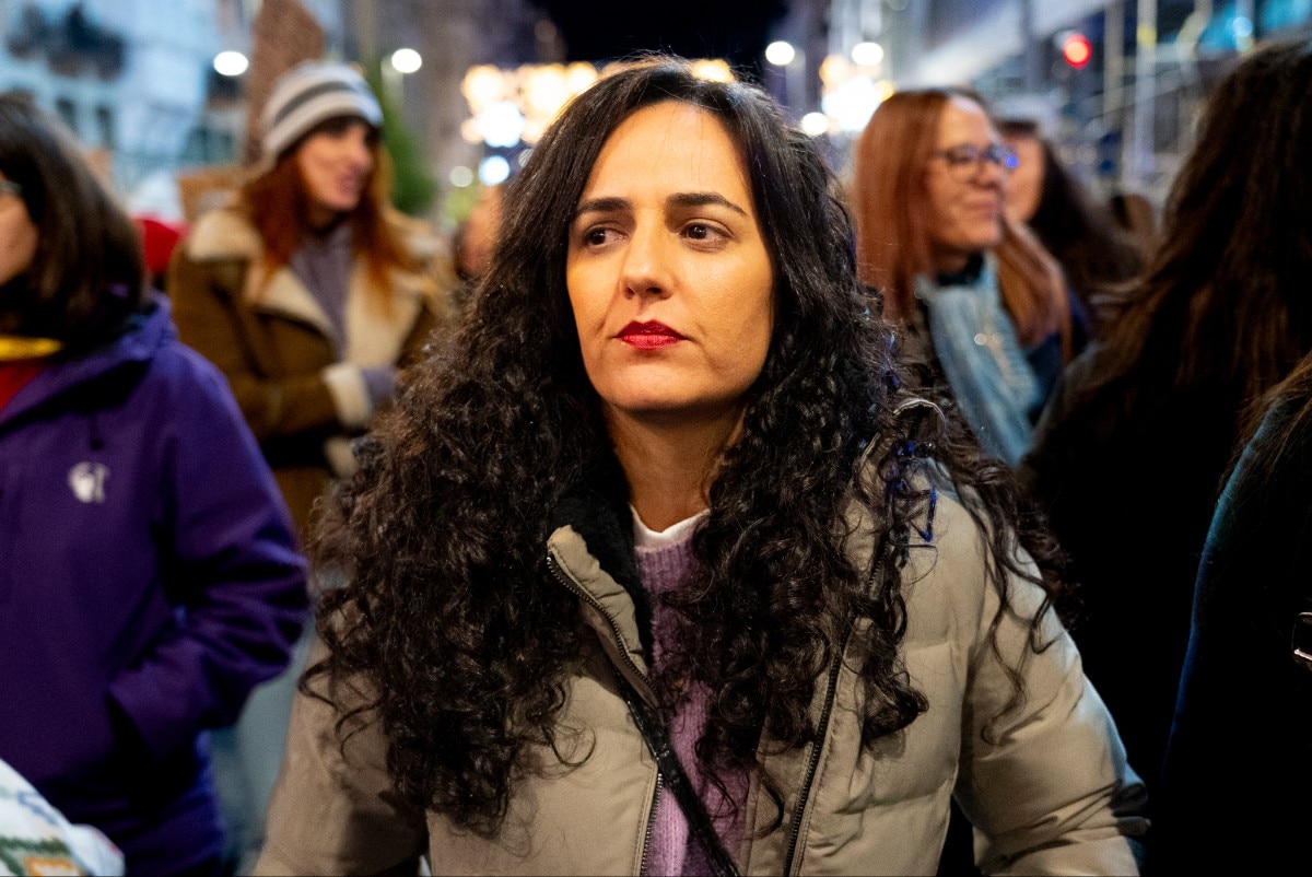 Uma mulher parada ao ar livre à noite, olhando.