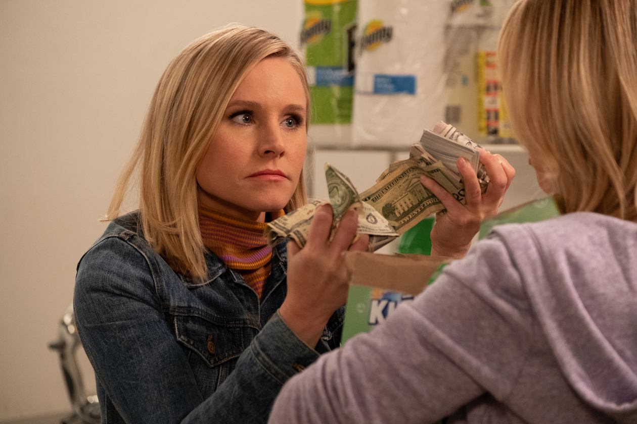 Eleanor Shellstrop holding money in front of a woman in The Good place