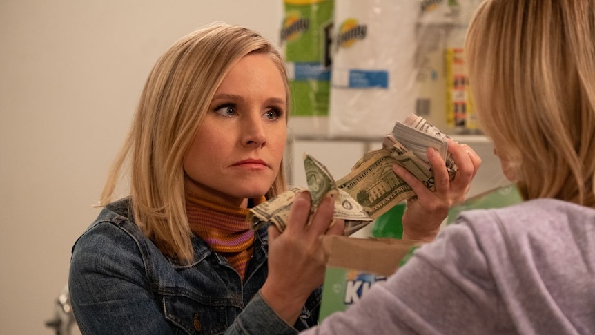 Eleanor Shellstrop holding money in front of a woman in The Good place