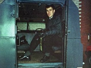 A man in a police uniform sits in armoured vehicle.