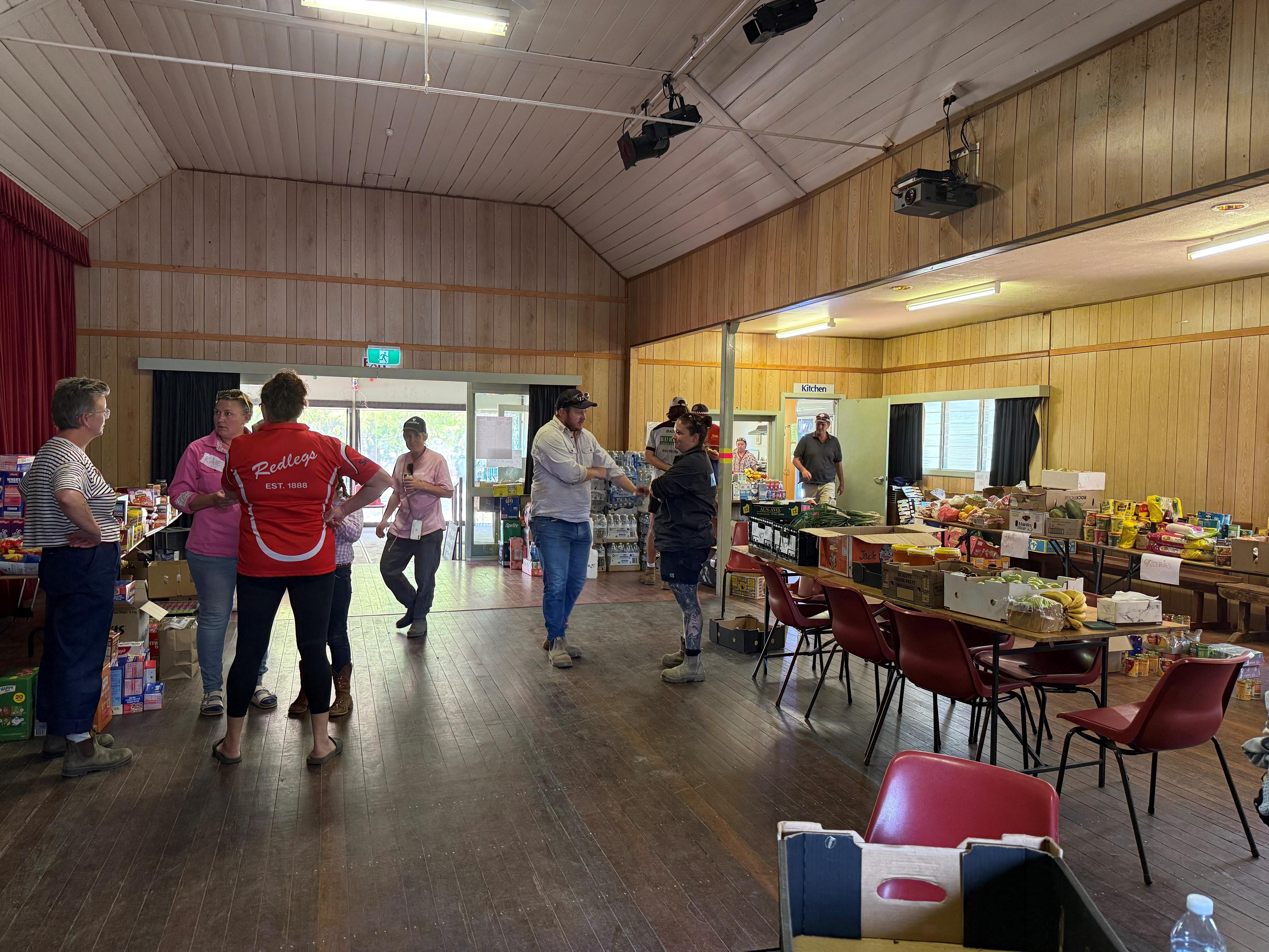 Un salón comunitario lleno de gente y mesas llenas de comida. 