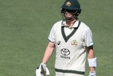 Steve Smith carries the bat and looks disappointed as he walks off