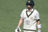 Steve Smith carries the bat and looks disappointed as he walks off