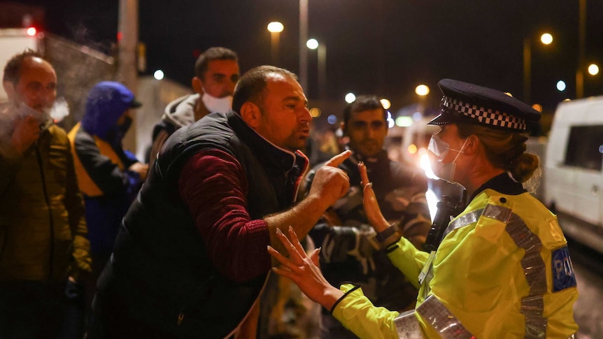 A person argues with a police officer while waiting to get on a ferry in Dover, Britain.