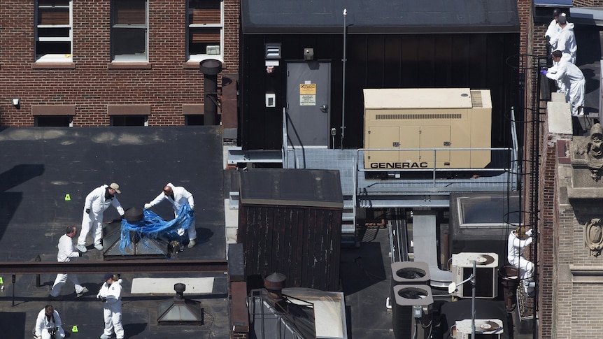 Officials investigate the rooftop of a building above the finish line of the Boston Marathon on April 18 2013.