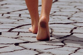 Woman walking barefoot across cracked earth (Thinkstock: iStockphoto)