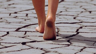 Woman walking barefoot across cracked earth (Thinkstock: iStockphoto)