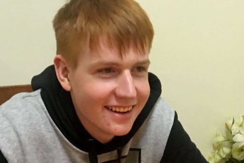 A teenage boy with red hair smiling