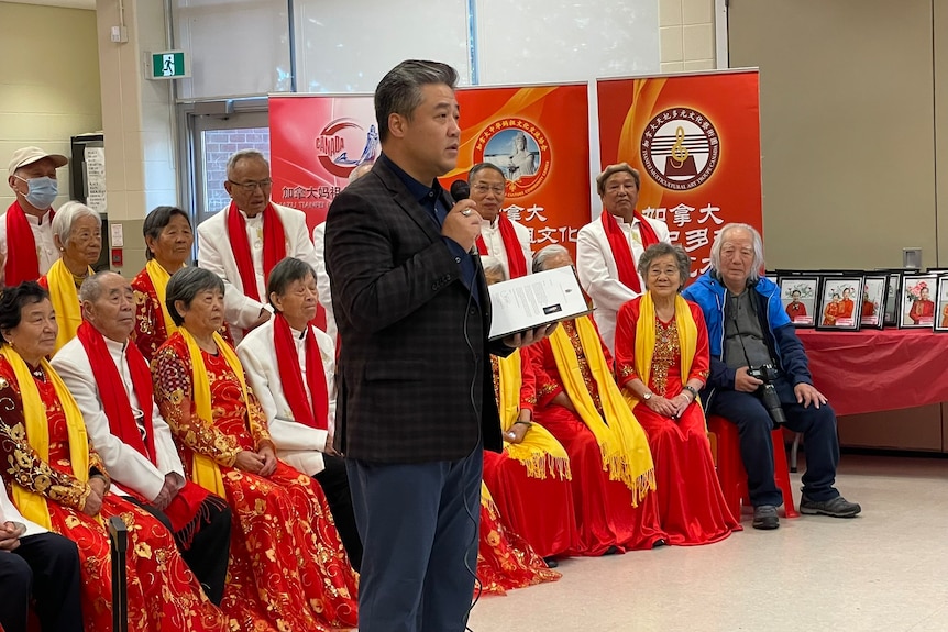 Han Dong stands at a Chinese community event speaking with a microphone