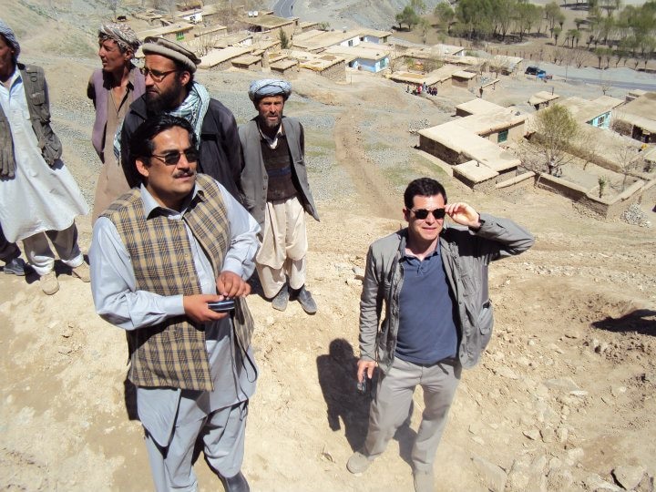 Habib ur Rehman and other stands on a hill overlooking a dusty Afghan village.
