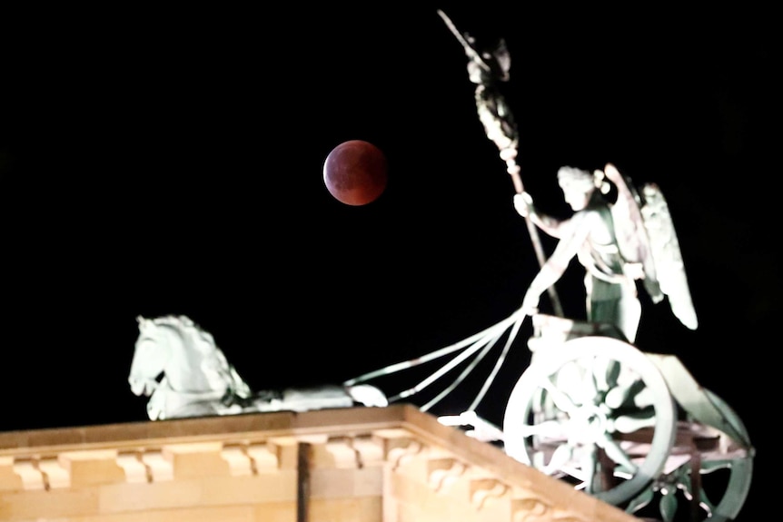 The Moon is seen during a lunar eclipse next to the Quadriga atop the Brandenburg Gate in Berlin.