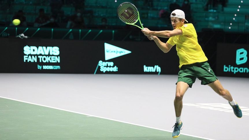 Australian tennis player Alex de Minaur in the action of hitting the ball during a match 