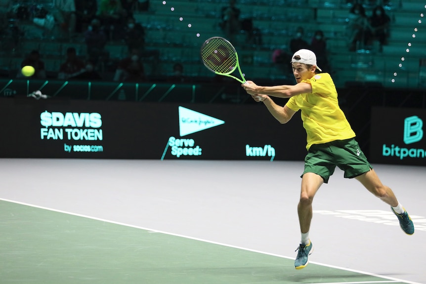 Australian tennis player Alex de Minaur in the action of hitting the ball during a match 