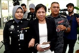 A woman surrounded by Malaysian police officers and media