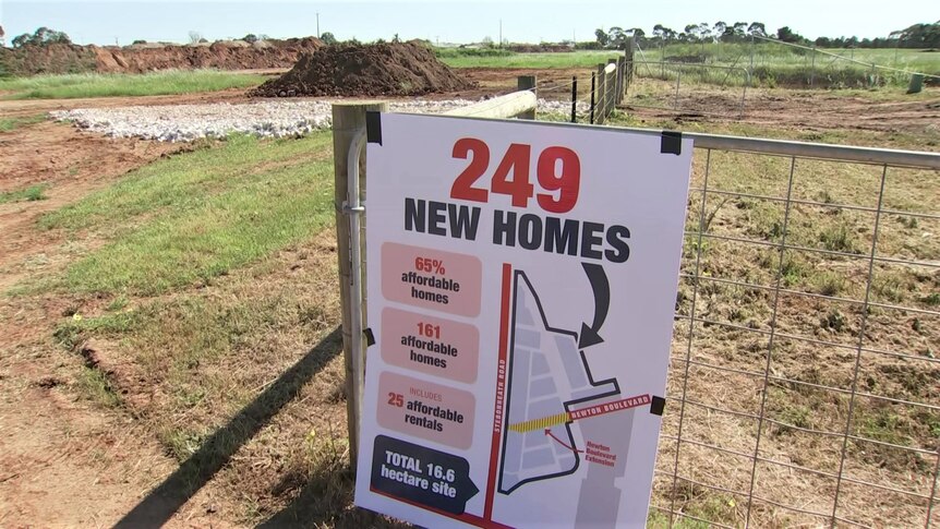 A sign which says "249 new homes" in front of a large vacant piece of land. 