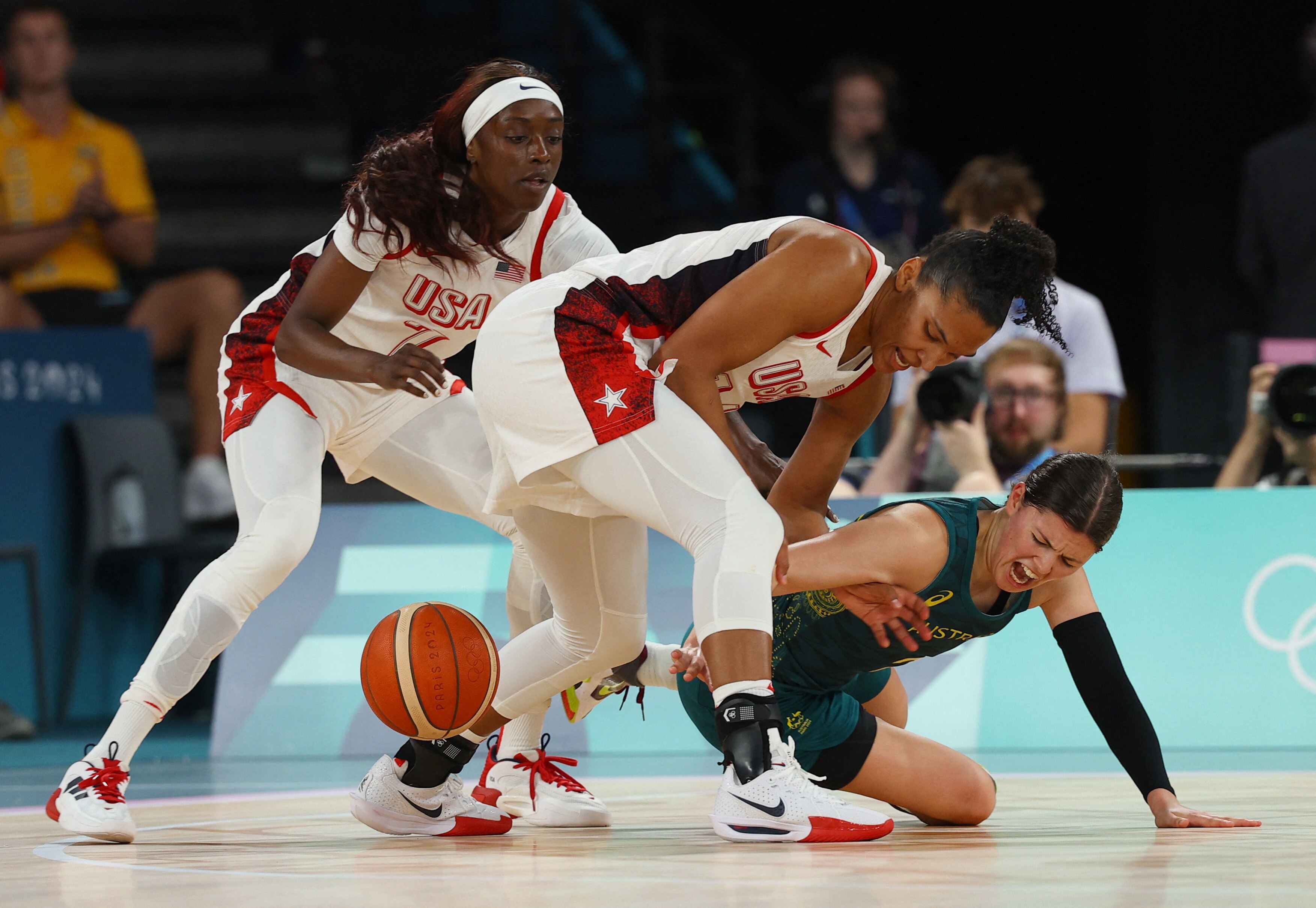 Jade Melbourne is on the ground trying to win the ball from two US players