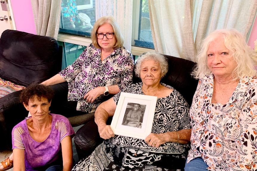 Four women sit on a couch looking sombre