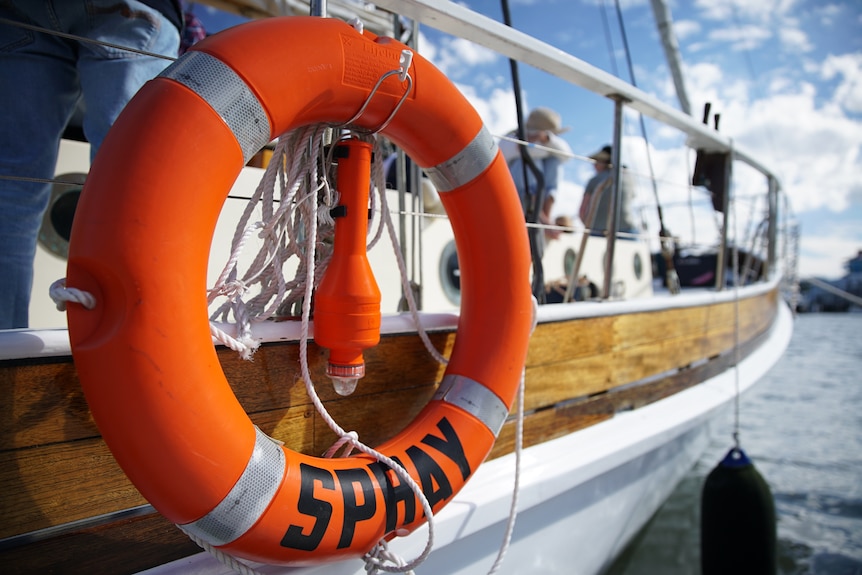 A life ring with the word 'Spray' written on it, hanging off a tall ship.