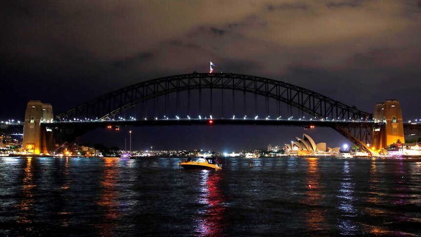 A combination photo shows the Sydney Harbour Bridge and Opera House in light (above) and darkness (below)