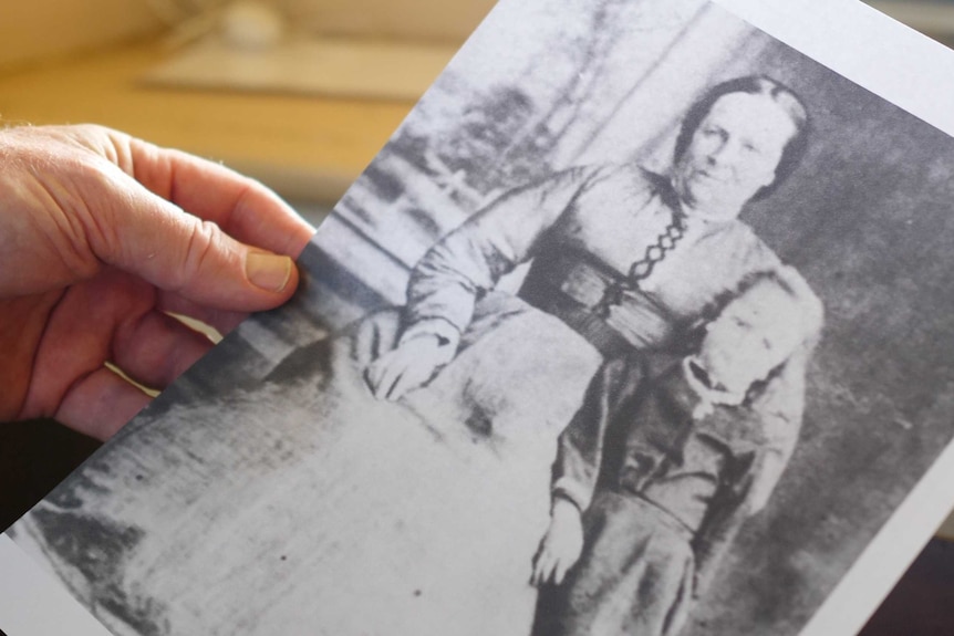 A man's hand holding a historical photo of Sophia Dent and one of her children.