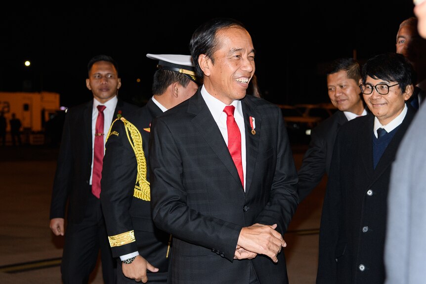 the president of indonesia arrives at an airport as he is greeted by officials