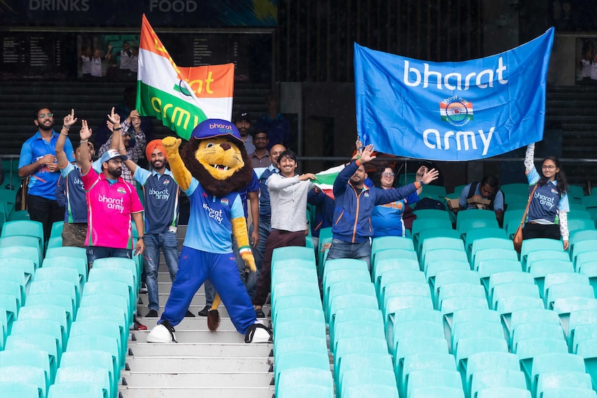 Indian fans, including a mascot, stand in the crowd as rain falls at the SCG.