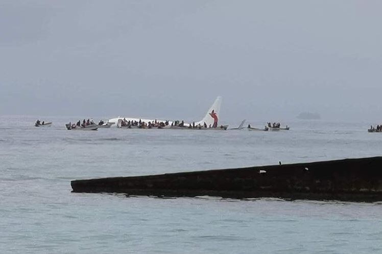 Air Niugini plane in ocean with people scrambling on top