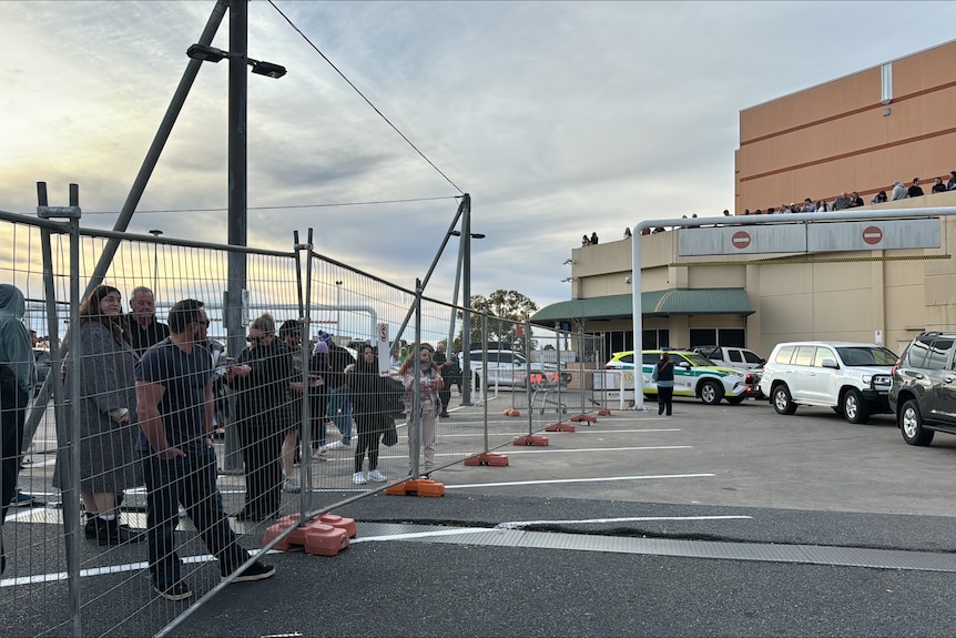 People gather behind fences outside Marion Shopping Centre.
