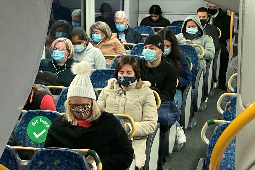 通勤的人戴着口罩坐在火车上。