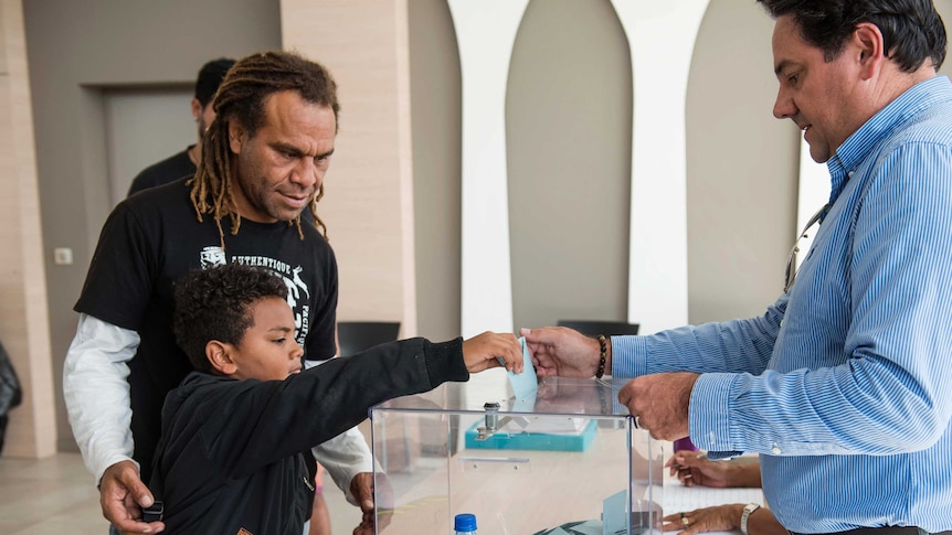 A boy helps his father voting in a voting station in Noumea, New Caledonia.