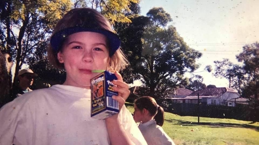 Josie Bober 小时候的一张老照片，她看着相机，喝着一盒果汁。 