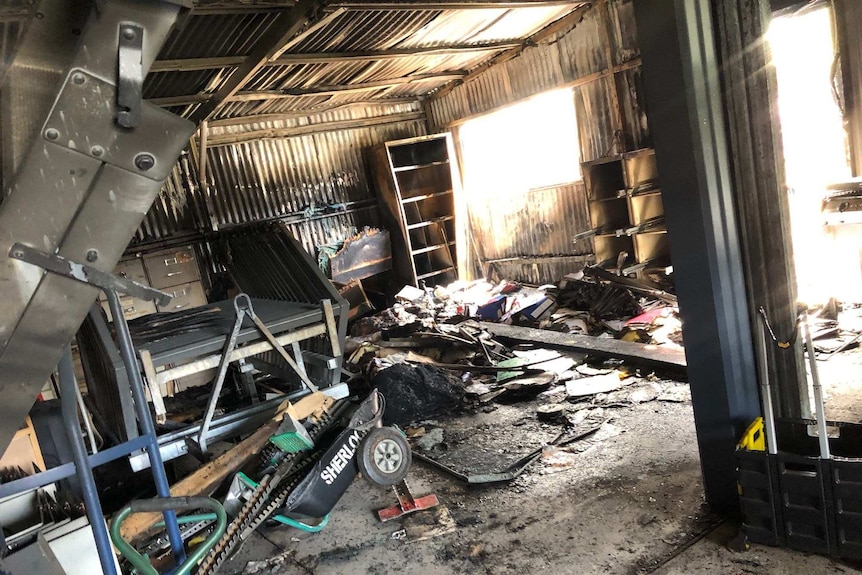 A burnt out shed with ash and ruined equipment on the floor.