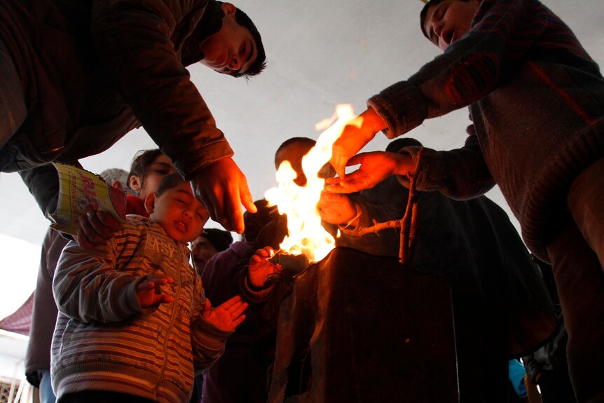Syrian refugees warm their hands at a fire in Tripoli, northern Lebanon.