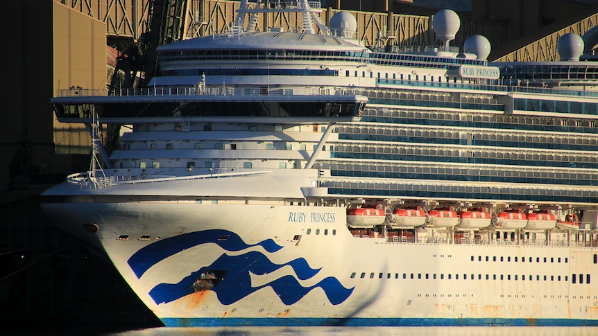 A picture of a huge cruise ship — the infamous Ruby Princess — at what looks like an industrial dock.
